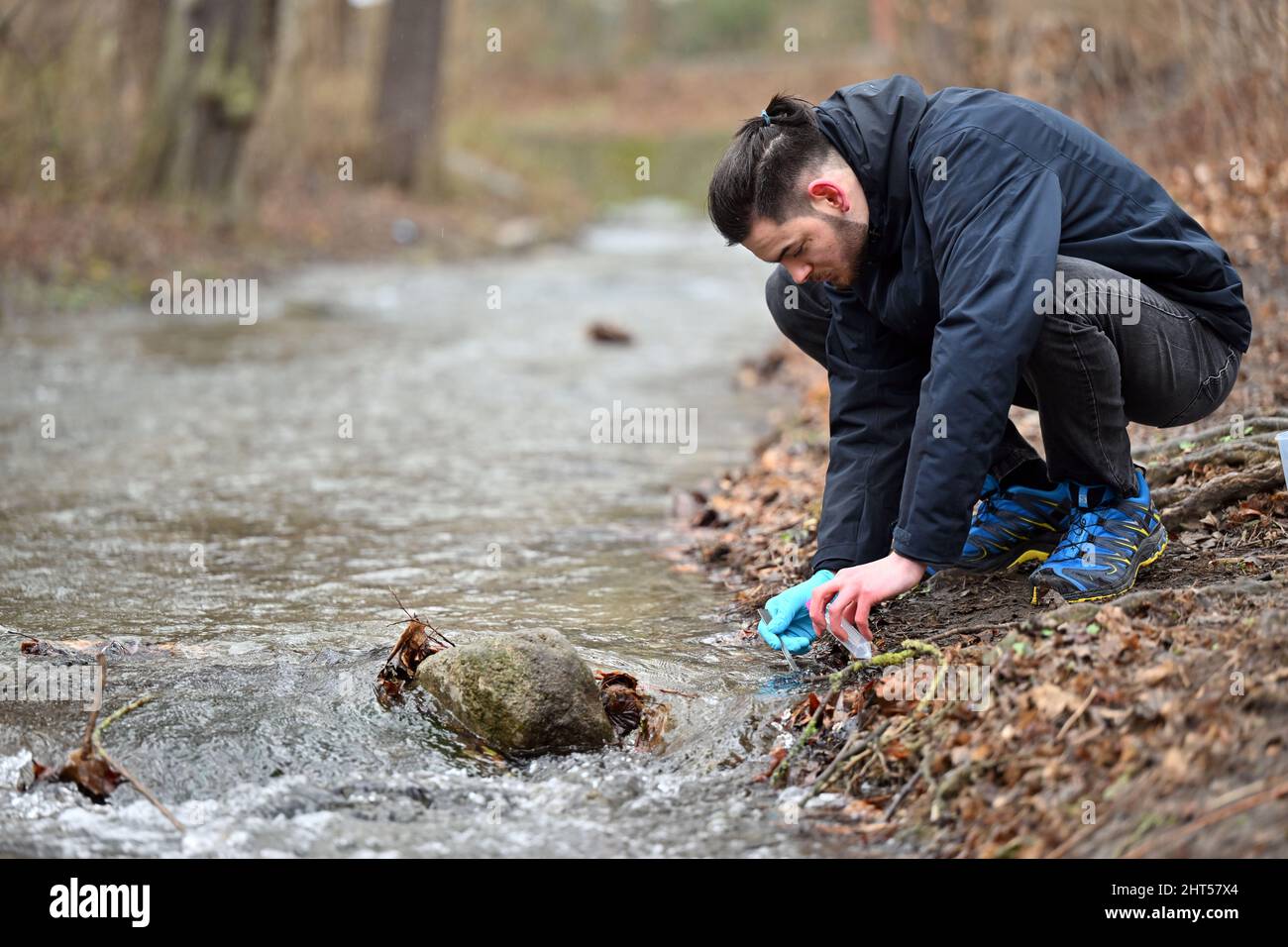 Jena, Deutschland. 25.. Februar 2022. Tom Haufschild, Ehrenstudent an der Friedrich-Schiller-Universität in Jena, sammelt am Ufer des Leutra-Flusses Bakterien. Er sucht nach sogenannten magnetotaktischen Bakterien, die sich am Magnetfeld der Erde ausrichten. Quelle: Martin Schutt/dpa-Zentralbild/dpa/Alamy Live News Stockfoto