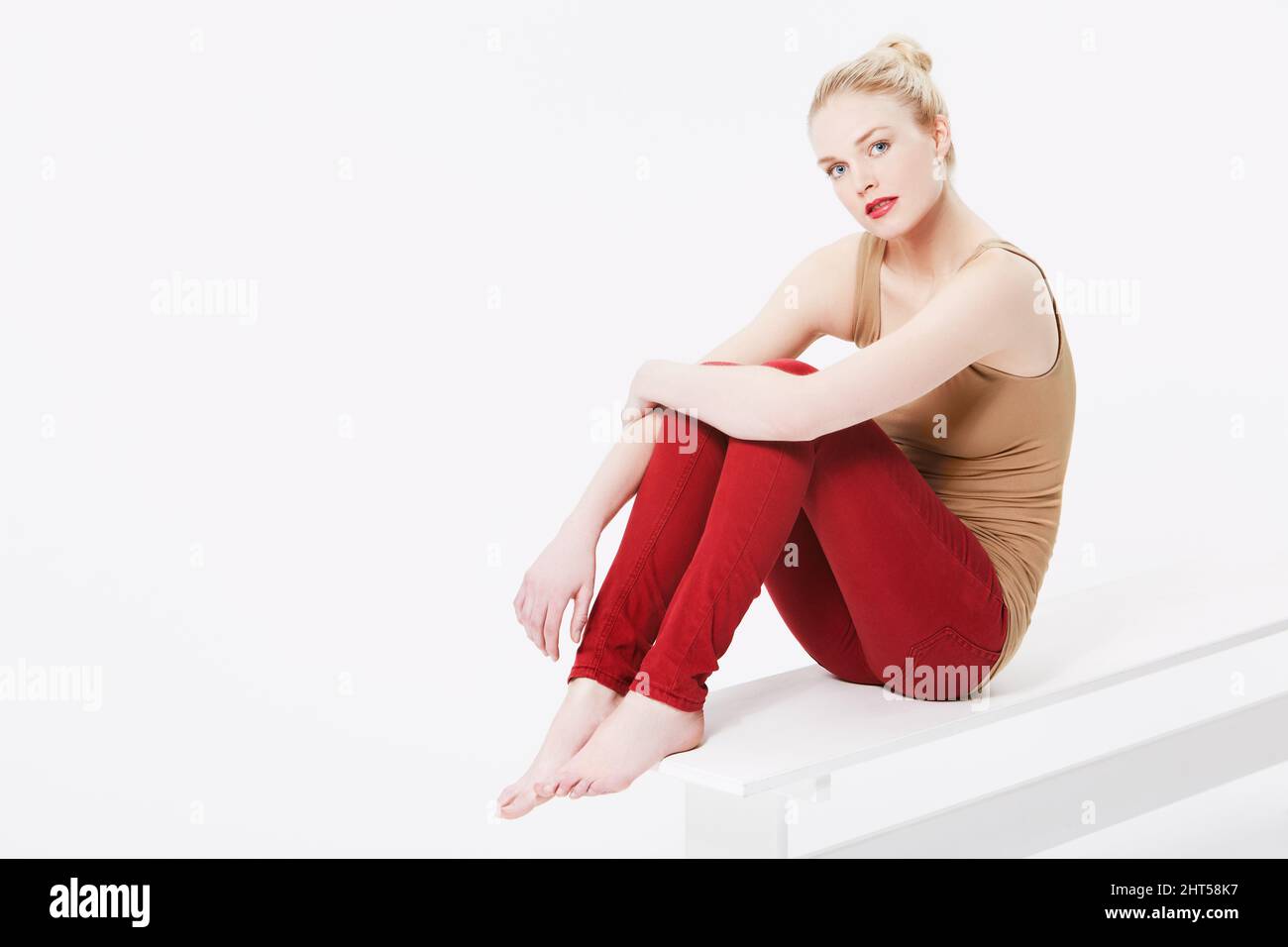 Lässige Schönheit. Porträt einer schönen Blondine in lässiger Kleidung, die in einem Studio sitzt. Stockfoto
