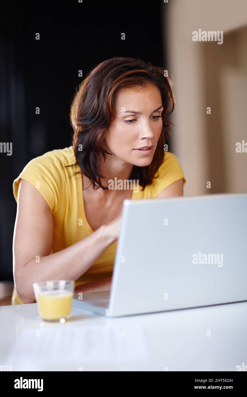Erste Nachrichten. Eine junge Frau, die zu Hause an ihrem Laptop arbeitet. Stockfoto