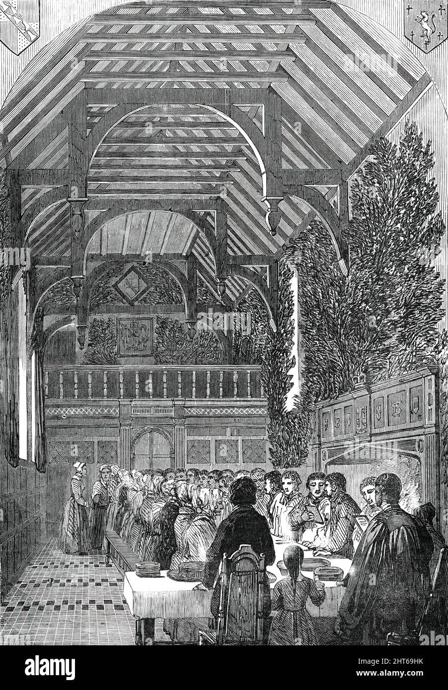 Palmsonntag in der Halle des Sackville College, East Grinstead, [Sussex]. 1850. Dieser Saal, bis vor kurzem als Spülküche genutzt, ist ein geräumiger, hoher Raum mit einem offenen Eichendach aus drei Buchten, der untere Teil mit dunkler Eiche getäfelt, Und eine Galerie aus dem gleichen Material am Westende. Die Wände sind mit Schilden geschmückt, die die Arme der verschiedenen Zweige der Familie Dorset tragen. Auf der einen Seite befindet sich ein großer offener Kamin mit einem lodernden Holzfeuer; über das obere Ende und in der Mitte befindet sich ein massiver Eichentisch. Um diese herum wurden die gealterten Bewohner des Dorfes gesammelt, Stockfoto