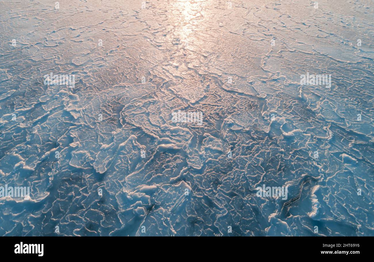 Luftaufnahme von oben nach unten auf die Eisoberfläche. Gefrorene Oberfläche des Meeres mit Sonnenreflexion Stockfoto