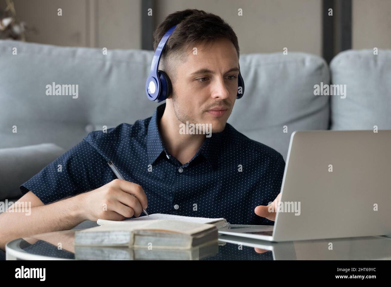 Konzentrierter junger Mann in Kopfhörern, der Online-Kurse studiert. Stockfoto