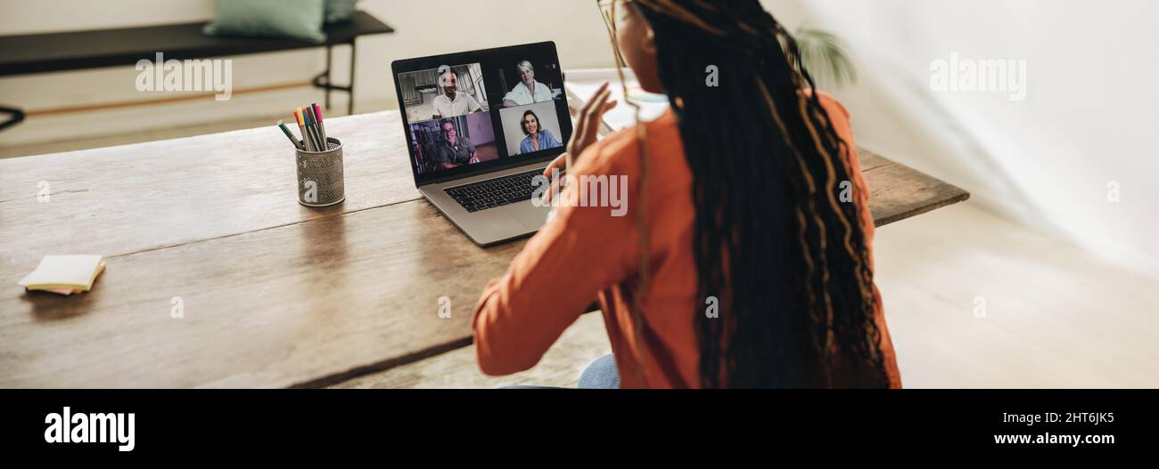 Freiberufliche Mitarbeiterin, die an einem virtuellen Treffen mit ihren Kunden teilnimmt. Junger Grafikdesigner, der einen Laptop für einen Videoanruf verwendet. Kreative junge Frau arbeitet o Stockfoto