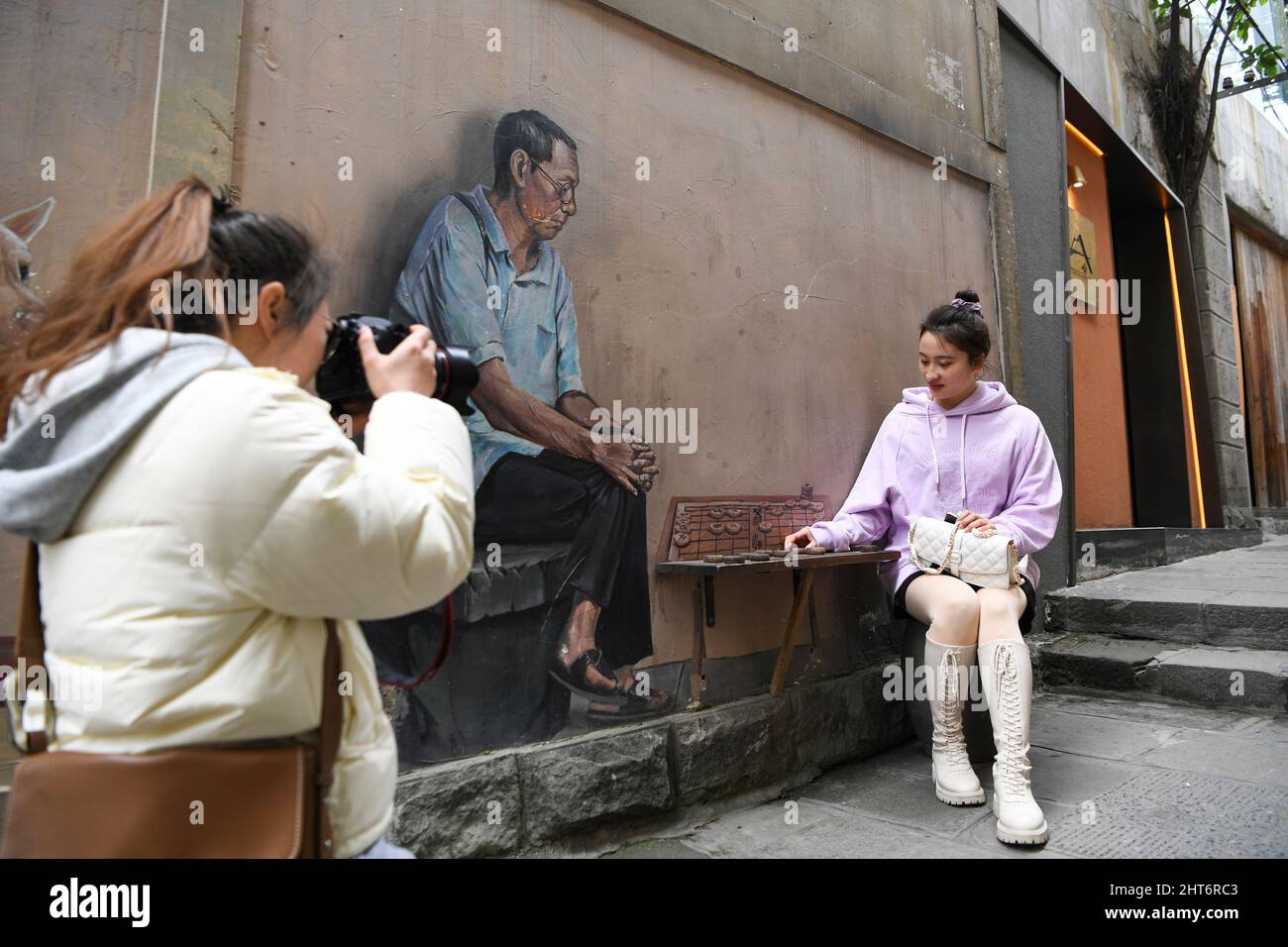 (220227) -- CHONGQING, 27. Februar 2022 (Xinhua) -- Ein Besucher macht Fotos in der Shancheng Alley in Chongqing, Südwestchina, 26. Februar 2022. Die Shancheng Alley liegt am Ufer des Jangtse-Flusses und wurde entlang von Bergen und Klippen erbaut. Es bewahrt viele historische Gebäude, die auf die Dynastien Ming (1368-1644) und Qing (1644-1911) zurückgehen. Die Regierung von Chongqing renoviert seit 2018 die Shancheng Alley und behält dabei ihre historischen und kulturellen Besonderheiten bei. Jetzt zieht das Gebiet Einheimische und Touristen mit seiner neuen Vitalität an. ( Stockfoto