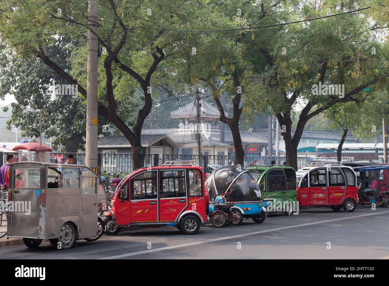 Eine Reihe von geparkten elektrischen Dreirad-Taxis in der Nähe des Eingangs zum Tao lief Ting Gong Yuan Park, Peking, China Stockfoto