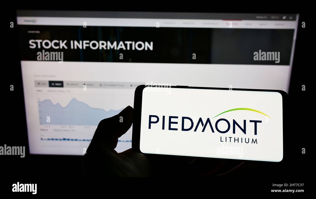 Person mit Mobiltelefon und Logo des amerikanischen Bergbauunternehmens Piedmont Lithium Inc. Auf dem Bildschirm vor der Webseite. Konzentrieren Sie sich auf die Telefonanzeige. Stockfoto
