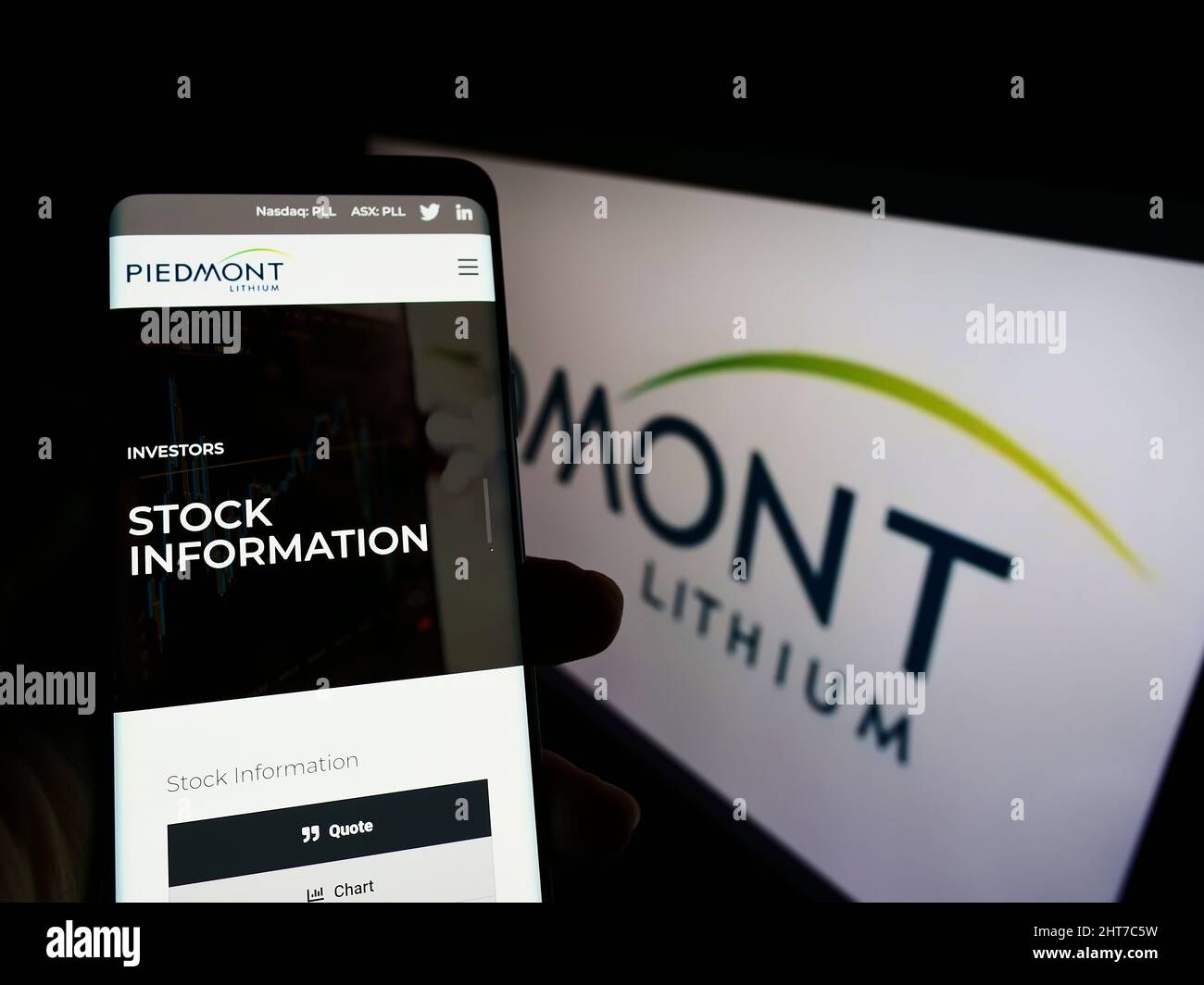 Person mit Mobiltelefon und Website des US-Bergbauunternehmens Piedmont Lithium Inc. Auf dem Bildschirm vor dem Logo. Konzentrieren Sie sich auf die Mitte des Telefondisplays. Stockfoto