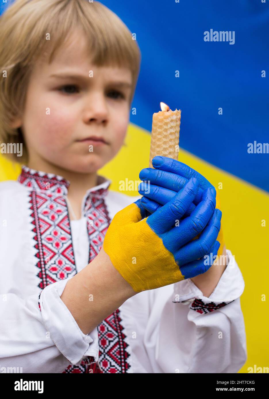 Kinderhände, gemalt in den Farben der ukrainischen Flagge, halten eine brennende Kerze. Ein Kindergeständnis, den Krieg in der Ukraine zu stoppen. Kinder gegen Krieg. Stockfoto