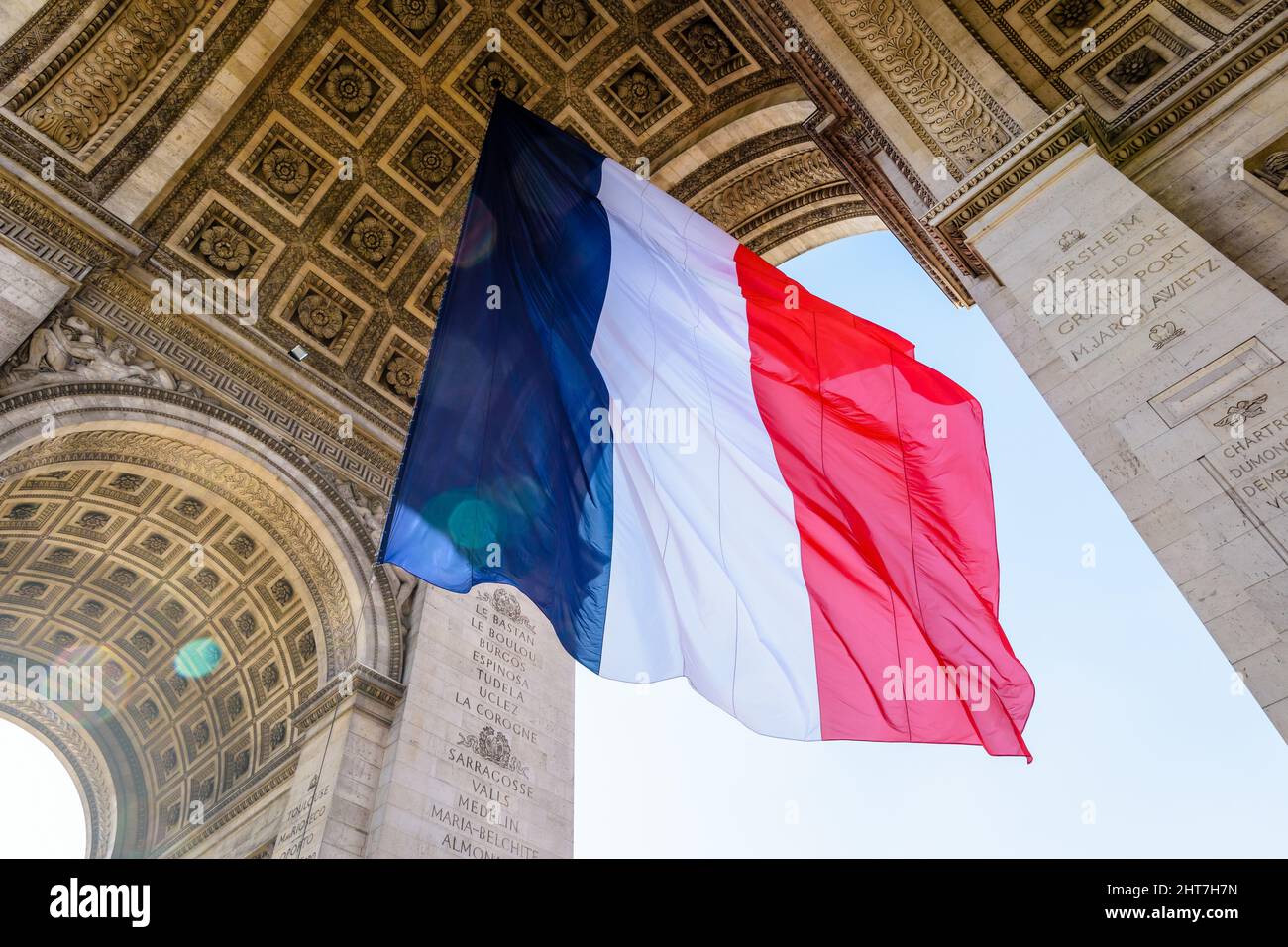 Niedrige Ansicht einer großen französischen Flagge, die unter dem Gewölbe des Triumphbogens in Paris, Frankreich, im Wind flattert. Stockfoto