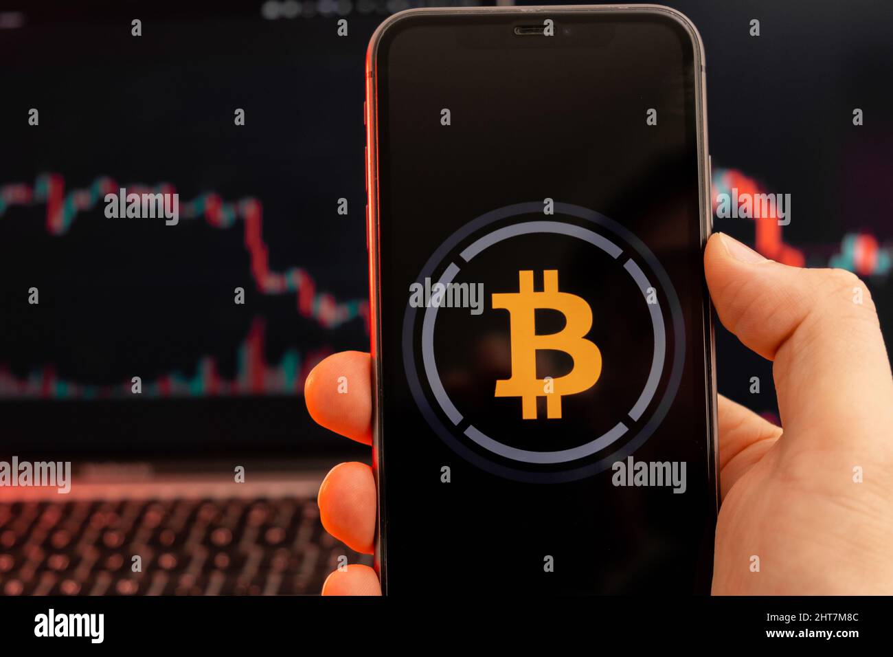 Bitcoin SV BSV Kryptowährung Logo auf dem Bildschirm des Smartphones in mans Hand mit Abwärtstrend auf dem Chart auf rotem Hintergrund, Februar 2022, San Francisco, USA. Stockfoto