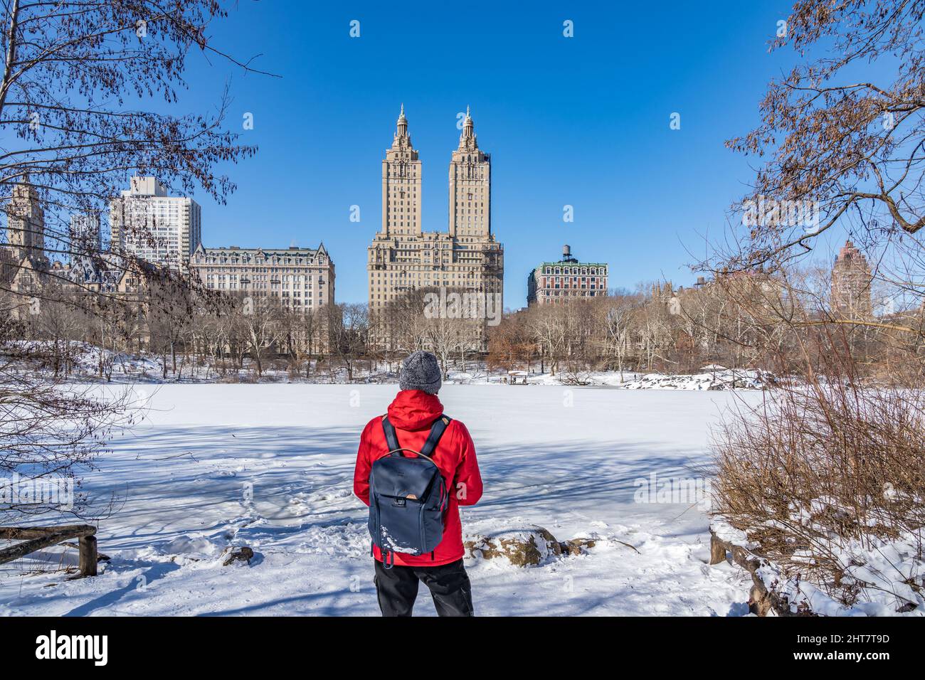 Ein Mann, der das berühmte Wahrzeichen von New York City betrachtet, überquert den schneebedeckten Fluss im Central Park Stockfoto