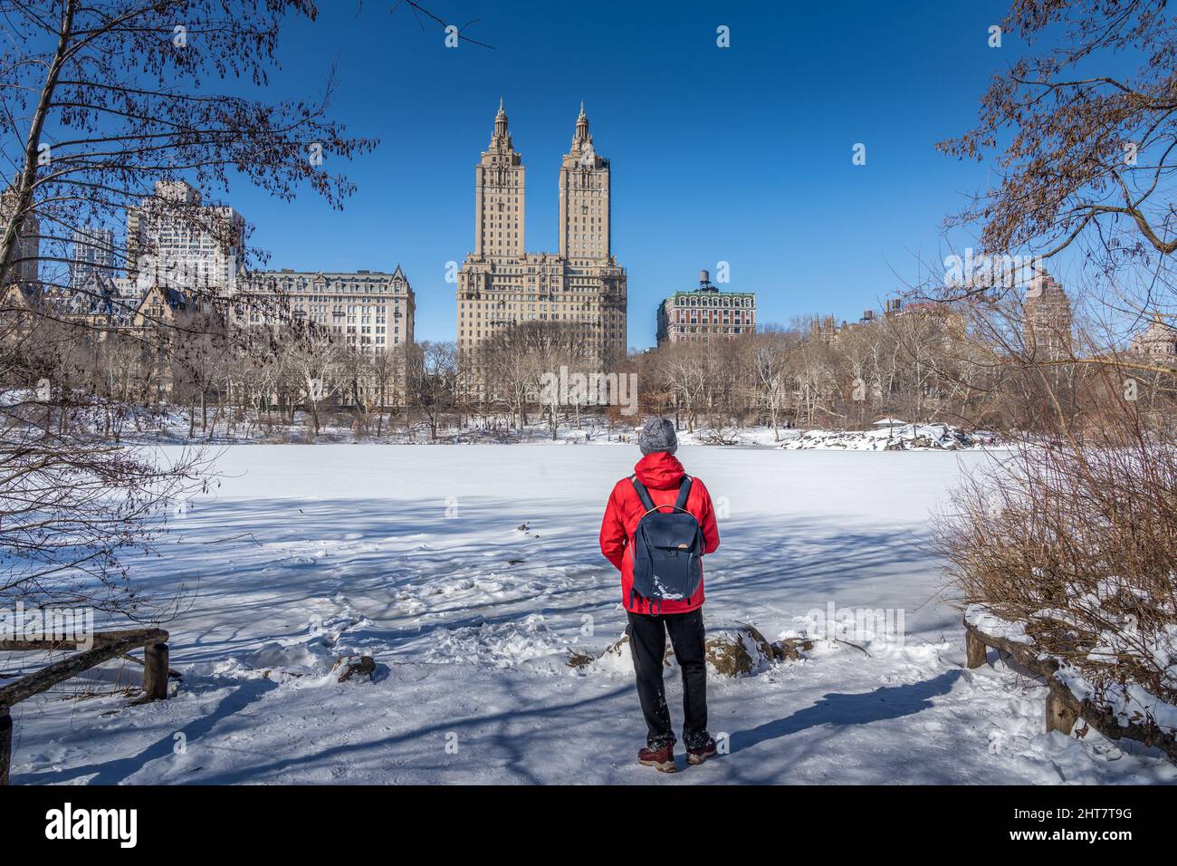 Ein Mann, der das berühmte Wahrzeichen von New York City betrachtet, überquert den schneebedeckten Fluss im Central Park Stockfoto