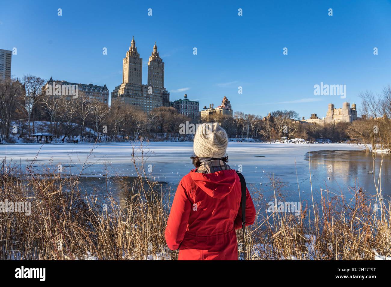 Frau im Central Park im eiskalten Winter mit Blick auf die wunderschöne Aussicht auf das historische Gebäude von New York City im oberen Westen. Stockfoto