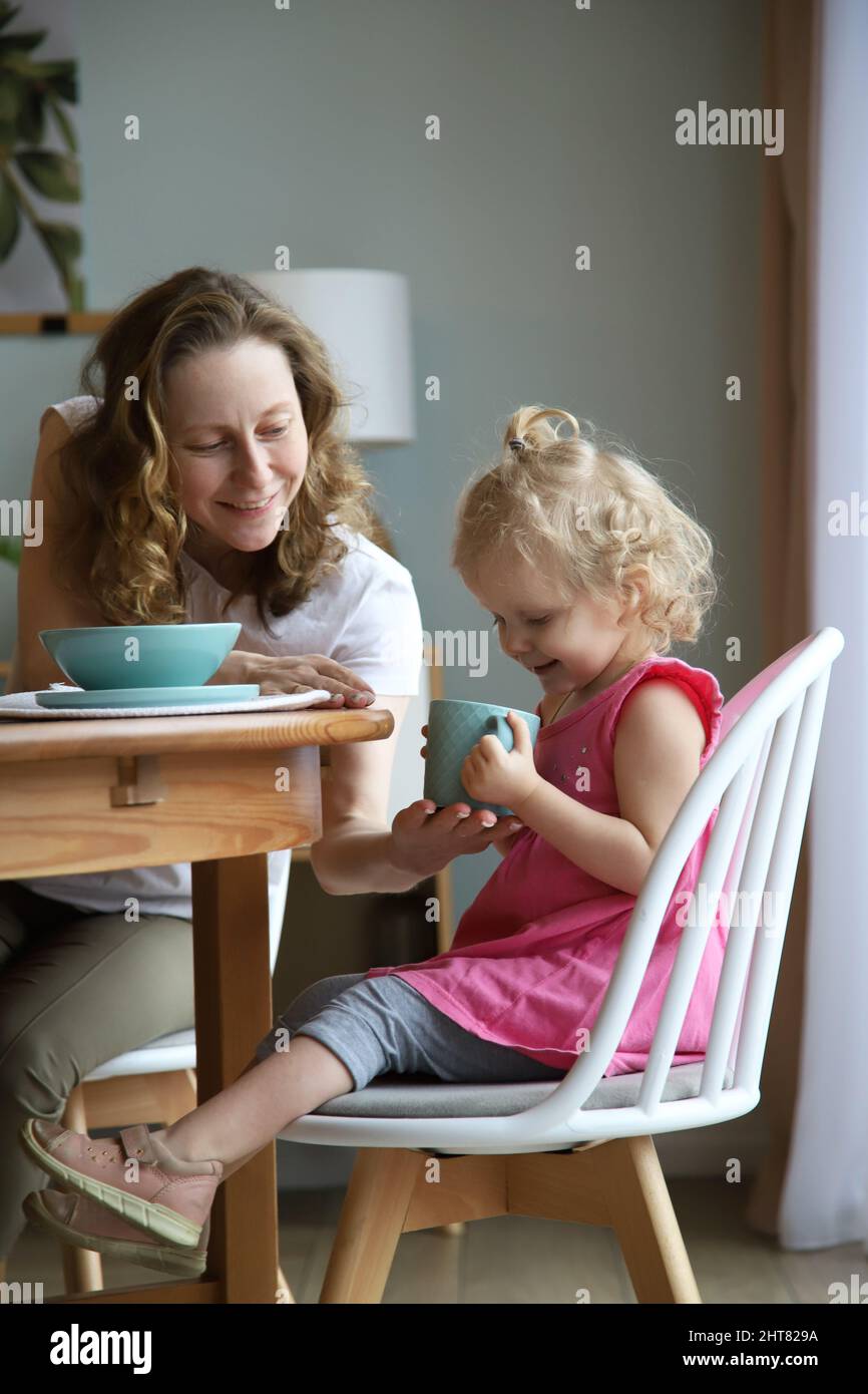 Mama gibt dem Baby einen Becher Stockfoto