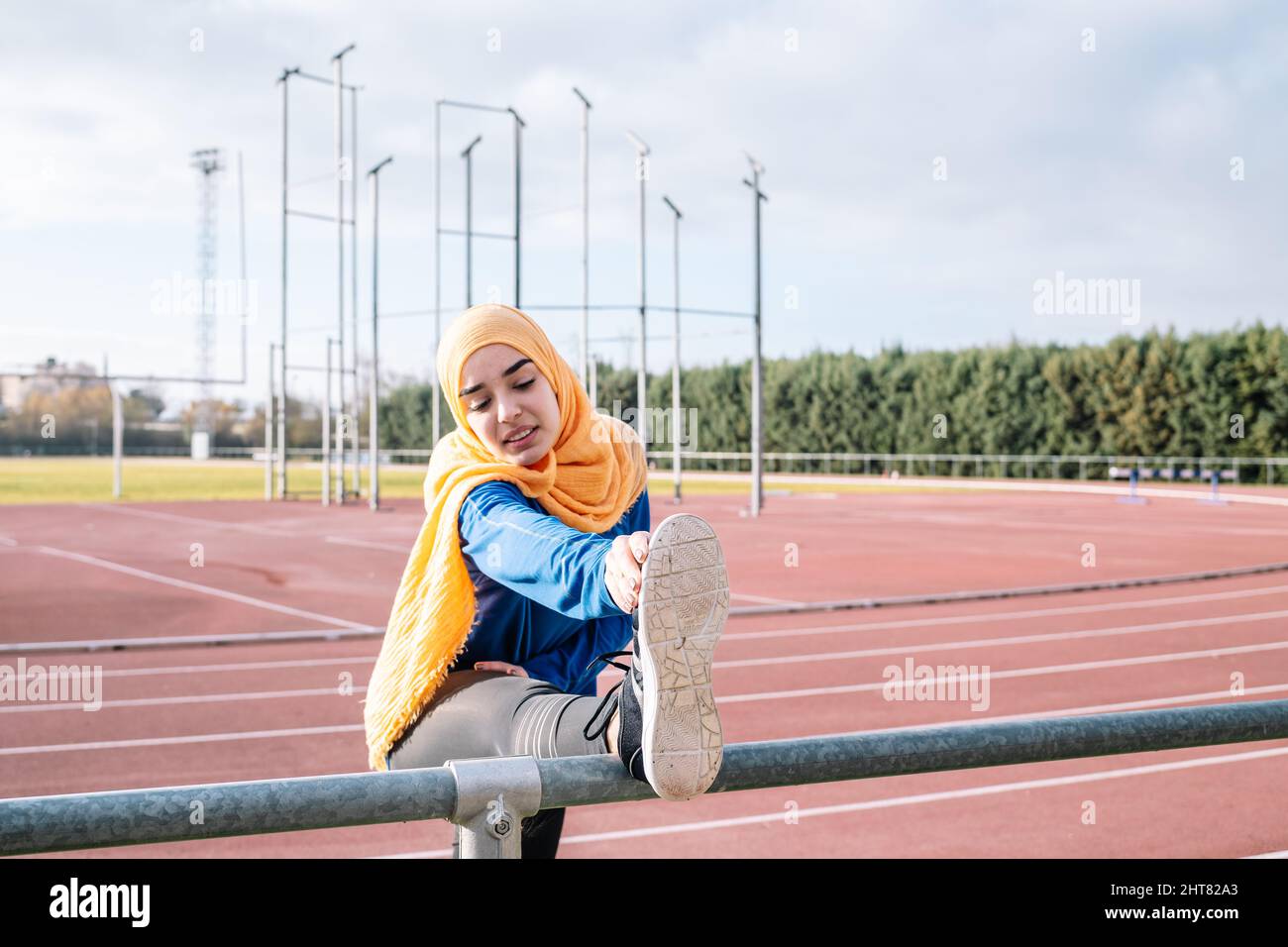 Arabische Frau, die während des Trainings die Beine im Stadion streckt Stockfoto