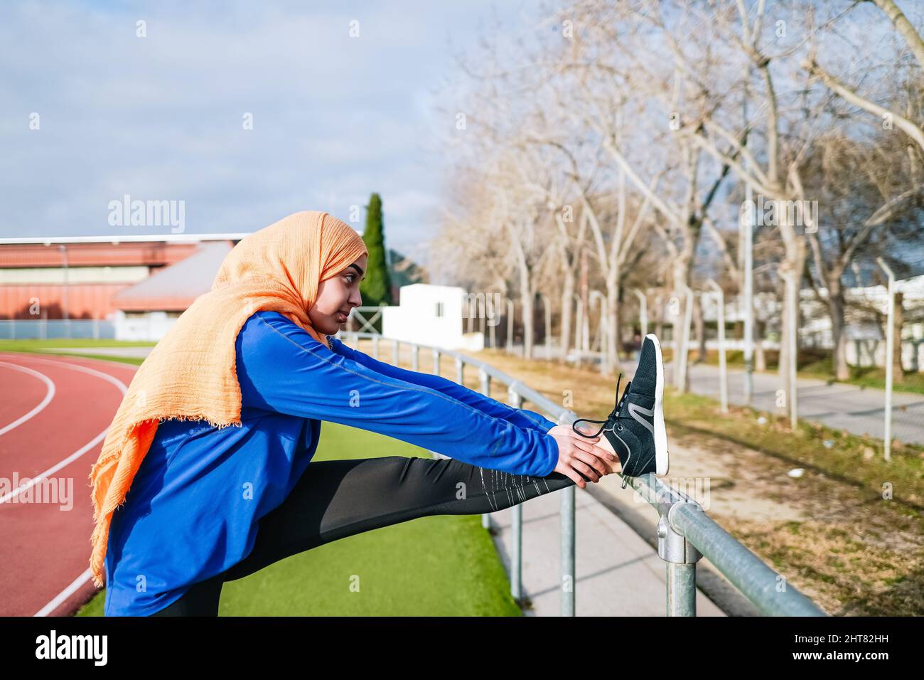 Muslimische ethnische Frau macht während des Trainings eine Dehnung der Oberschenkelmuskulatur Stockfoto