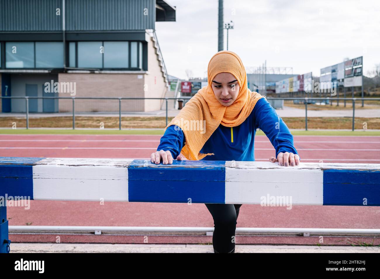 Arabische Frau macht Ausfallschritt-Übung auf der Rennstrecke Stockfoto