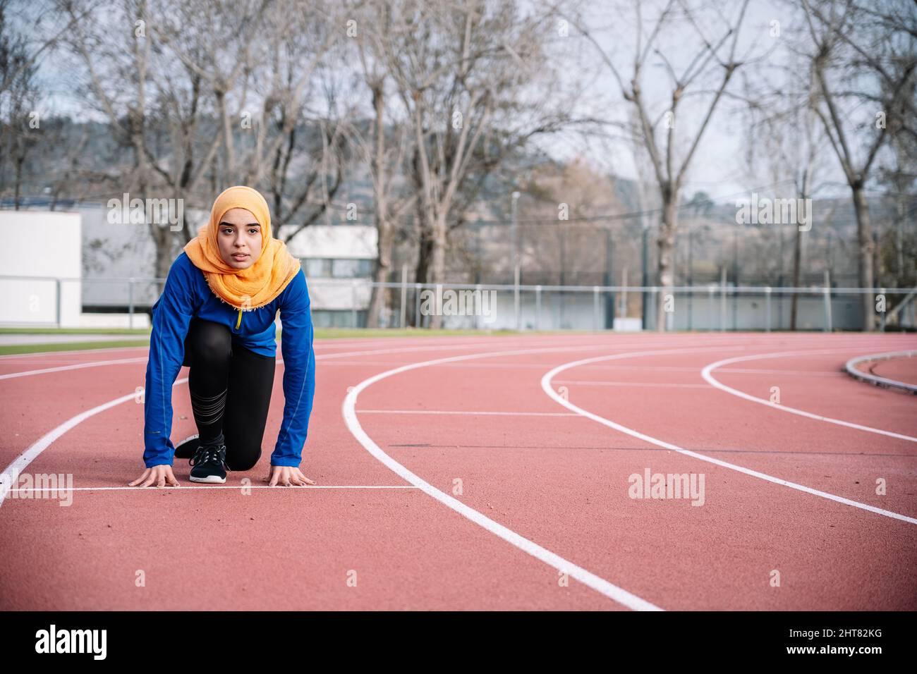 Seriöse ethnische Frau in Bereitschaftsstellung auf Laufstrecke Stockfoto