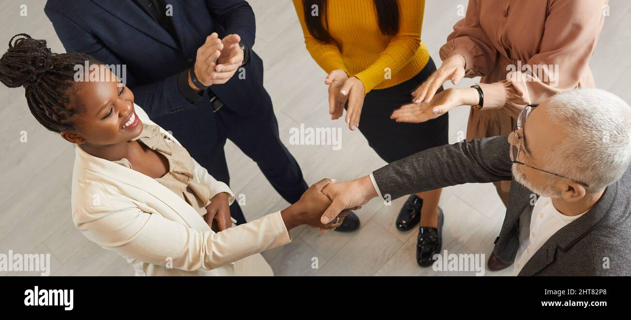Glückliche junge schwarze Frau tauscht Handshakes mit ihrem Chef oder Geschäftskollegen aus Stockfoto