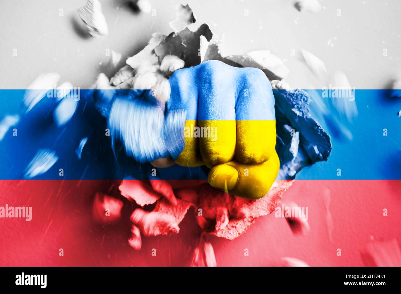 Eine Faust stanzt durch eine Betonwand mit den Farben der ukrainischen und russischen Flaggen. Das Konzept der Ukraine zerbricht die russische Armee und gewann im Krieg Stockfoto