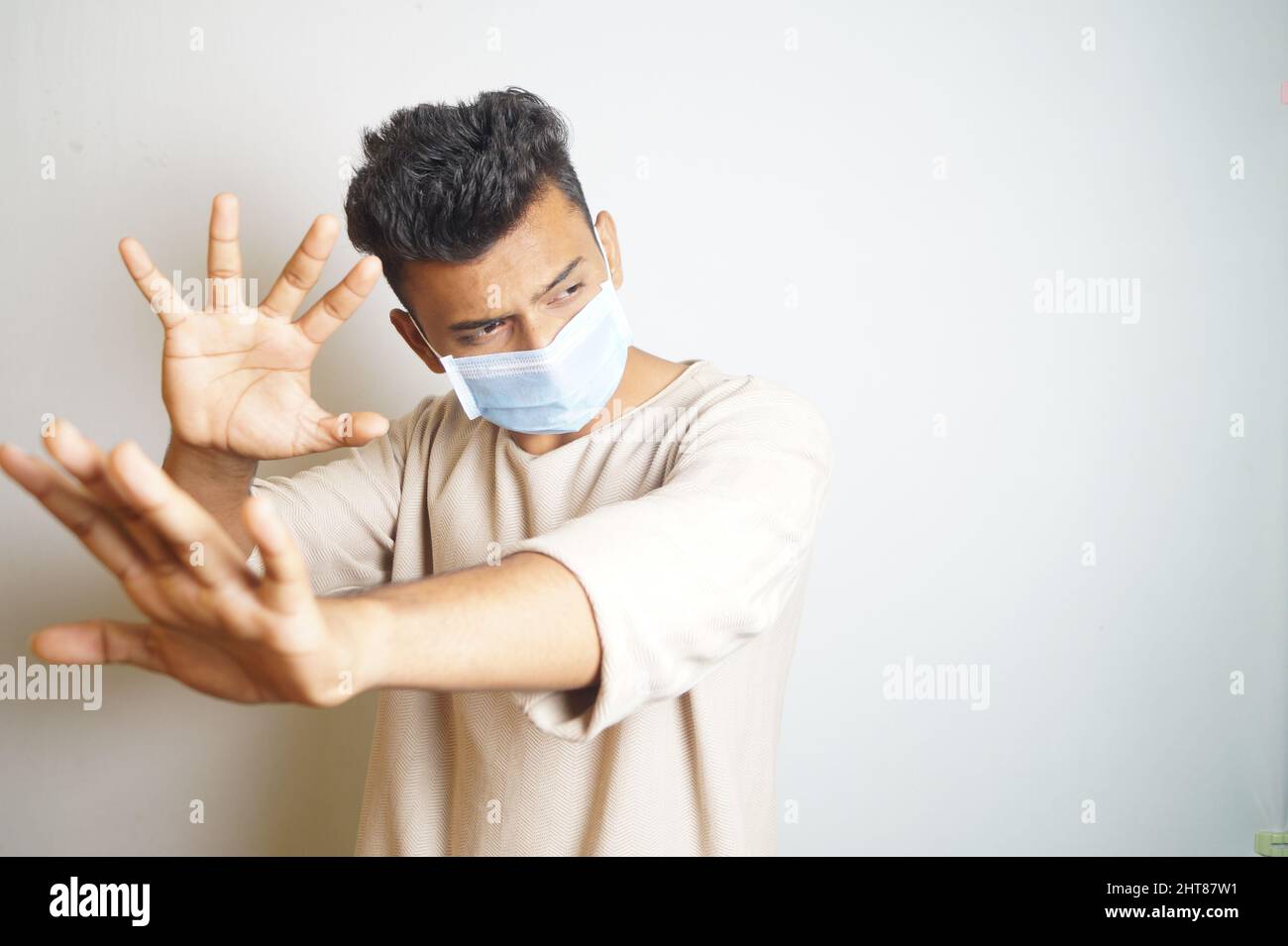 Ein junger Inder, der eine OP-Maske mit weißem Hintergrund trägt Stockfoto