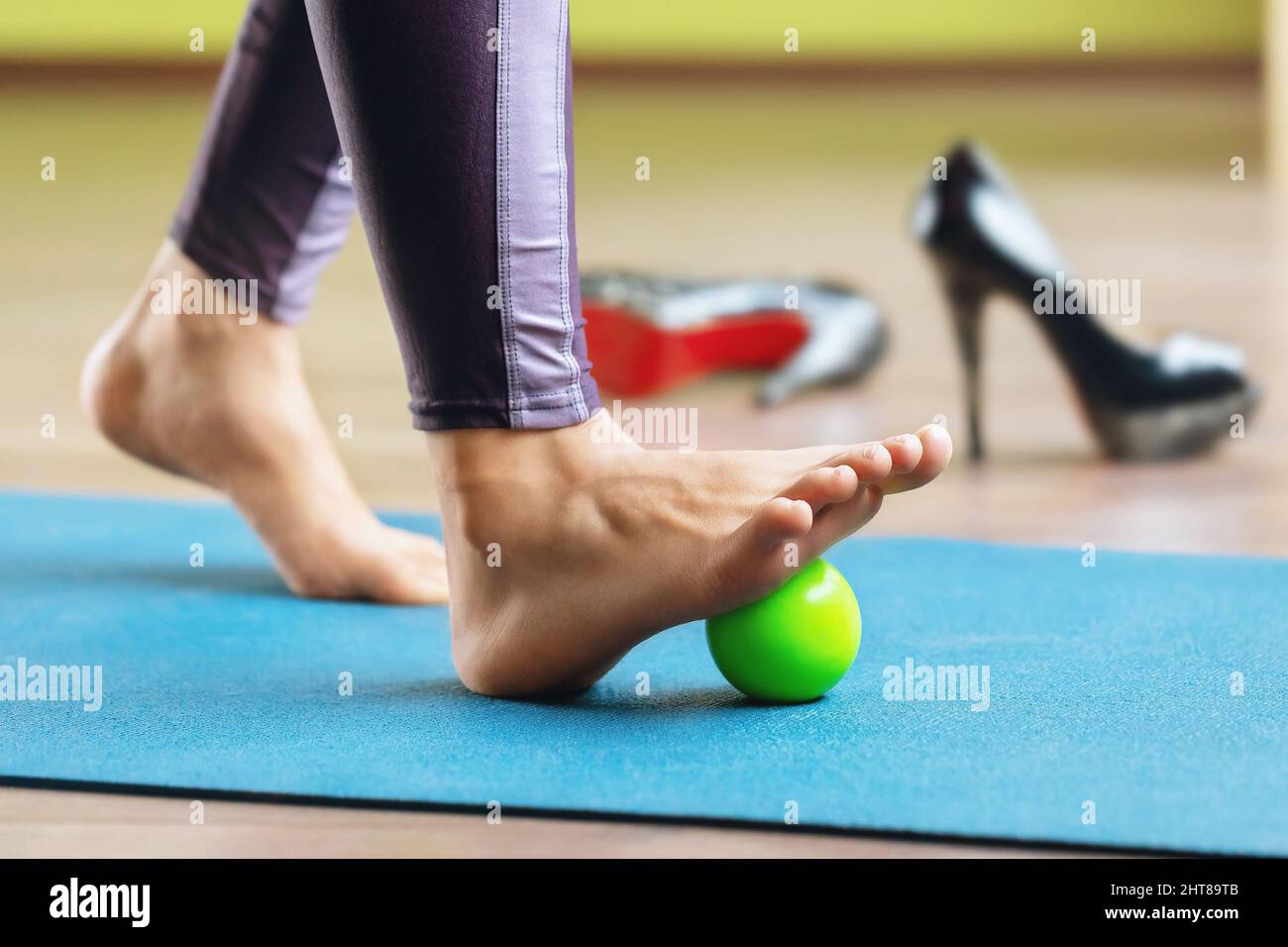 Myofasziale Entspannung der hypermobilen Fußmuskeln mit einem Massageball, der im Studio auf einer Matte steht. Verhinderung von Beinermüdung nach der Wehentraute Stockfoto