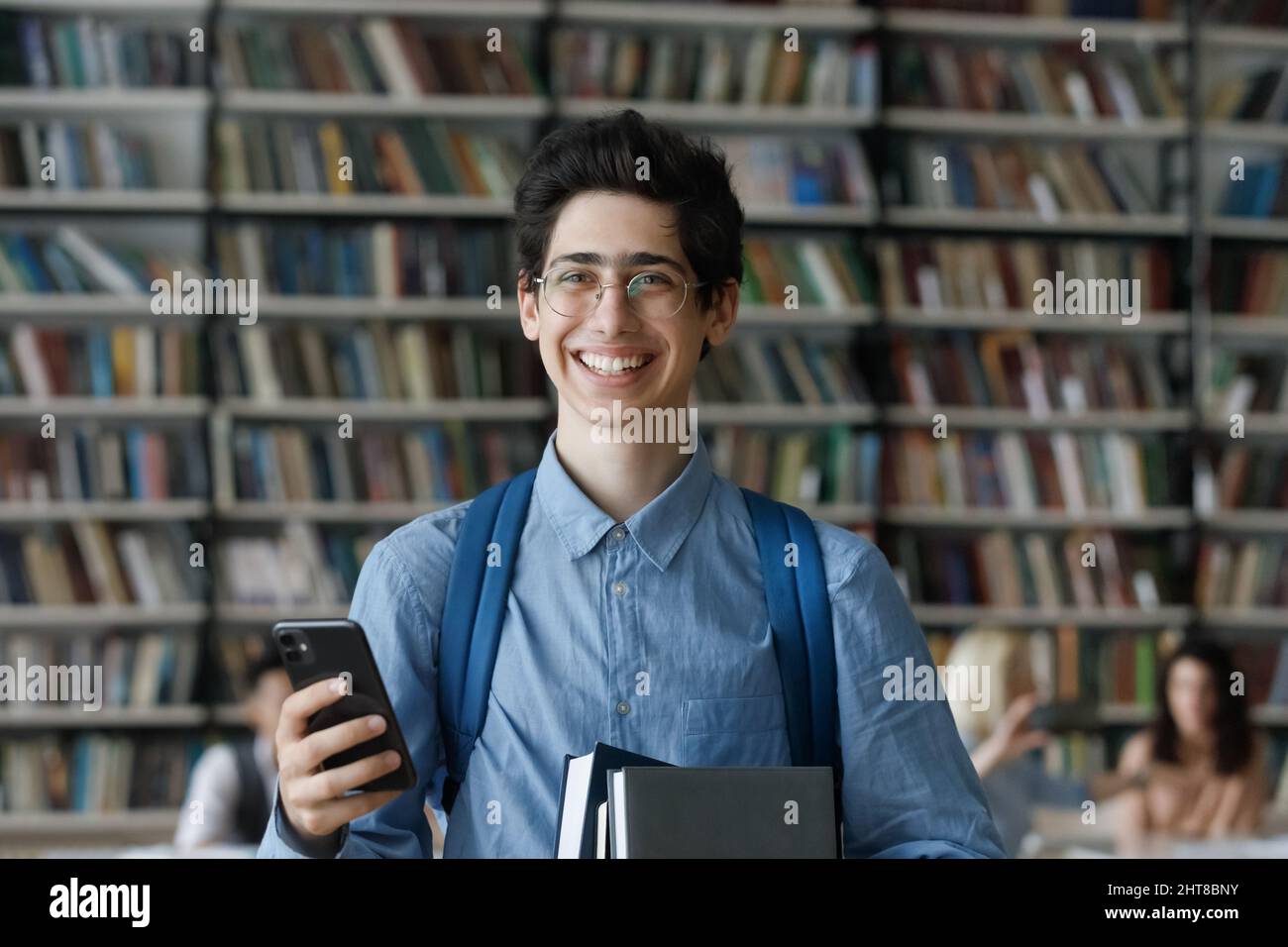 Porträt eines glücklichen jüdischen Studenten mit Telefon und Büchern. Stockfoto