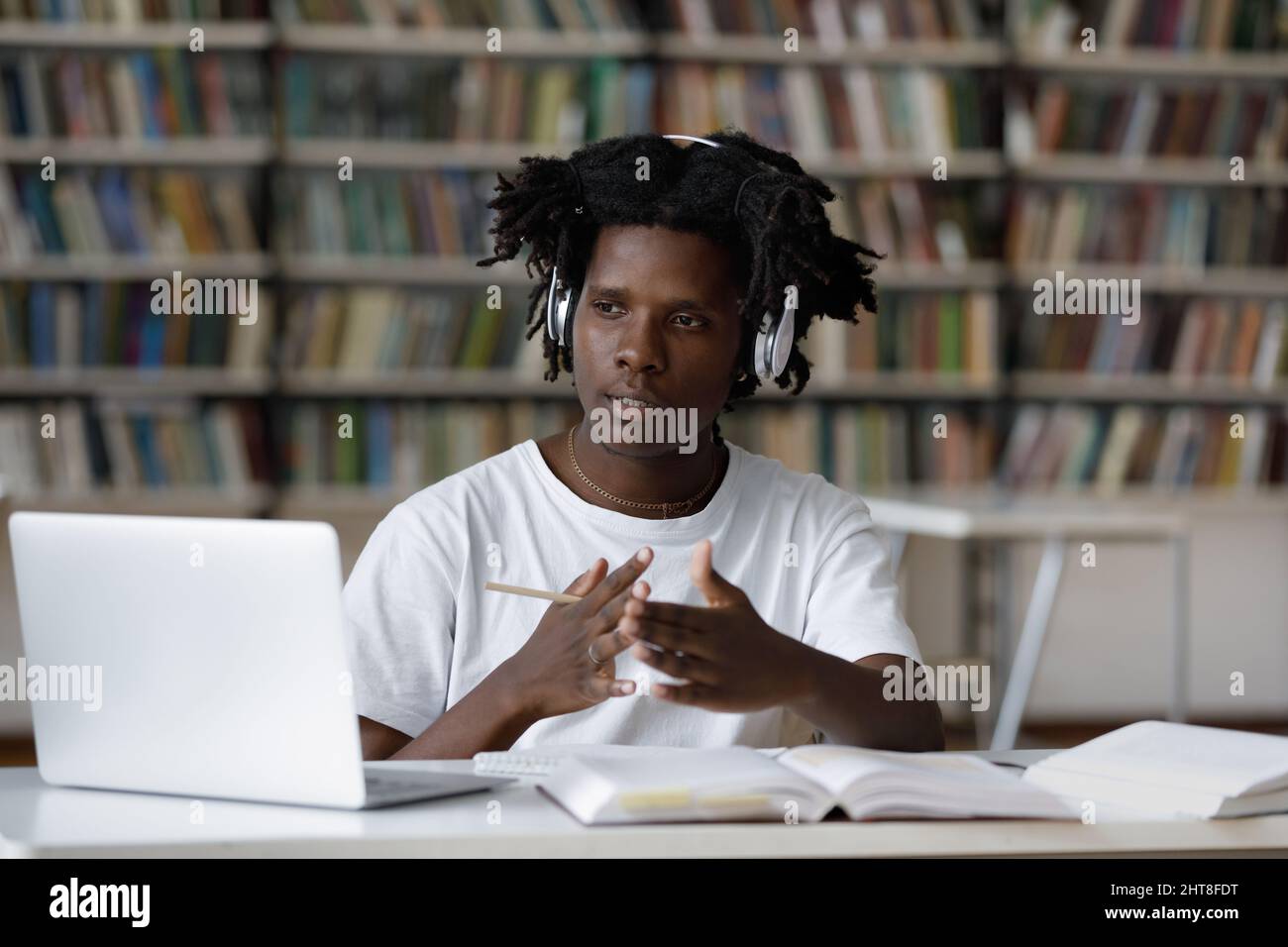 Konzentrierte junge afroamerikanische männliche Studentin e-Learning in der Bibliothek. Stockfoto