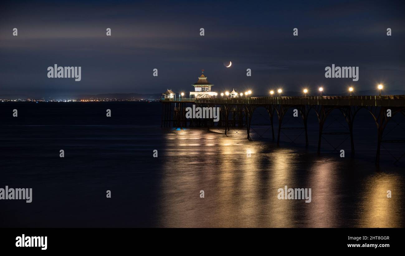 Ein Halbmond untergeht über dem Bristol Channel und dem Clevedon Pier in Somerset, England. Stockfoto