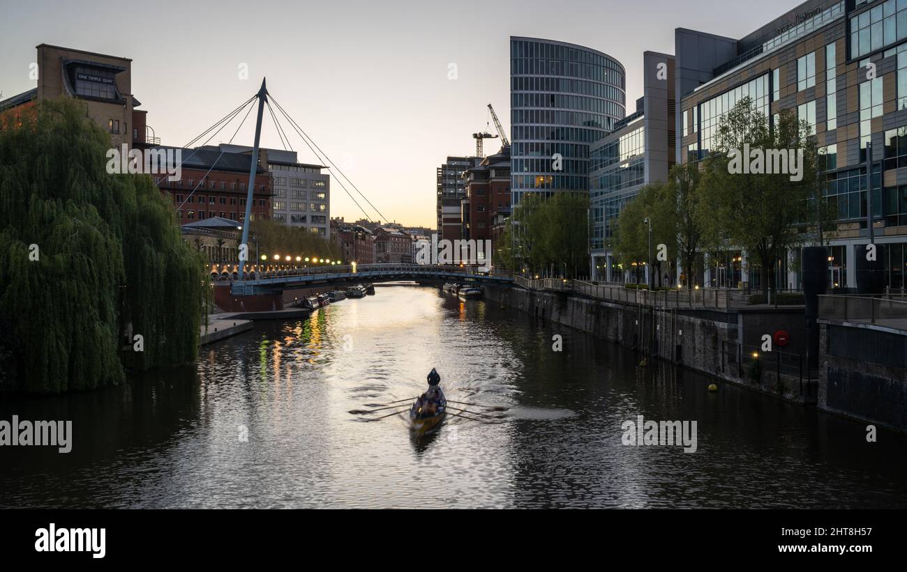 Ein Ruderteam fährt bei Sonnenuntergang am Temple Quay am schwimmenden Hafen von Bristol unter der Valentine's Bridge vorbei. Stockfoto