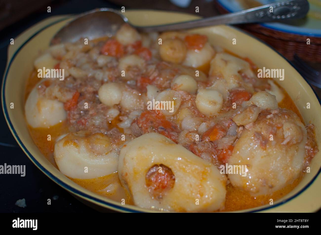 Schüssel mit gekochten Kartoffeln gefüllt mit Thunfisch, Tomaten und Eiern. Servierlöffel. Gastronomie zu Hause. Typisches asturisches Gericht Stockfoto