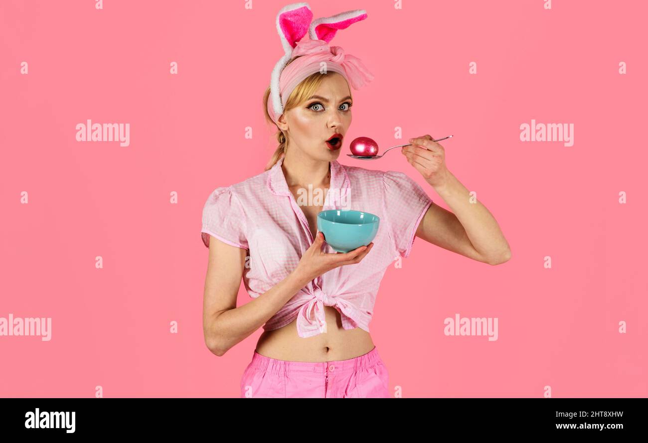 Ostertag. Frau mit rosa Ei auf Löffel. Überrascht Mädchen in Hasen Ohren. Eier färben. Auf der Jagd nach Eiern. Stockfoto