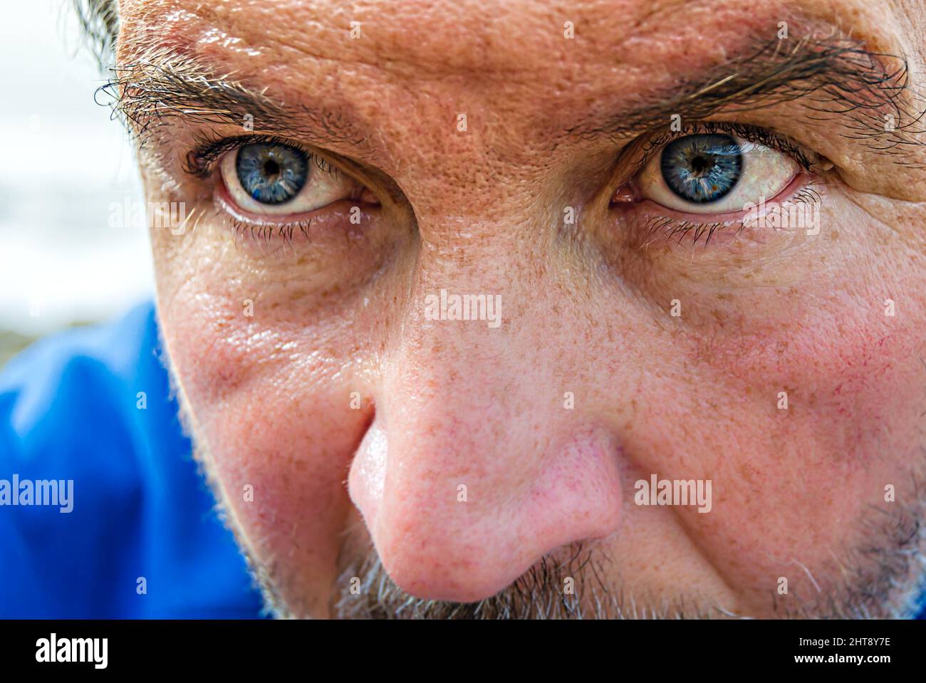 Porträt eines Mannes mit blauen Augen und einem blauen Bluse am Meer Stockfoto