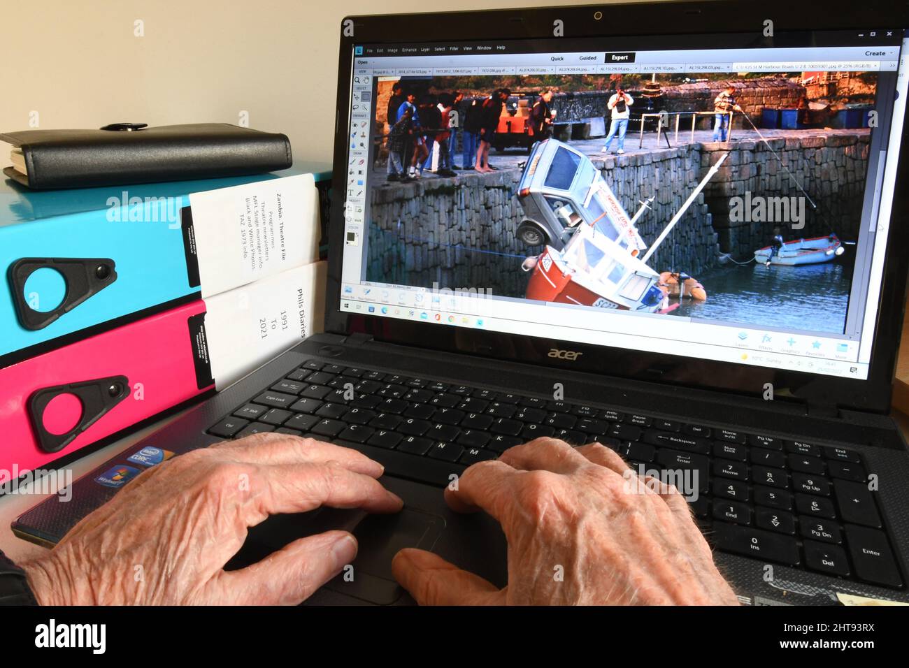 Alte Hände an einer Computertastatur, die Bilder finden, um angenehme Erinnerungen auszulösen, wenn man älter wird. Ferien bringen viele glückliche Erinnerungen und einige unfortun Stockfoto