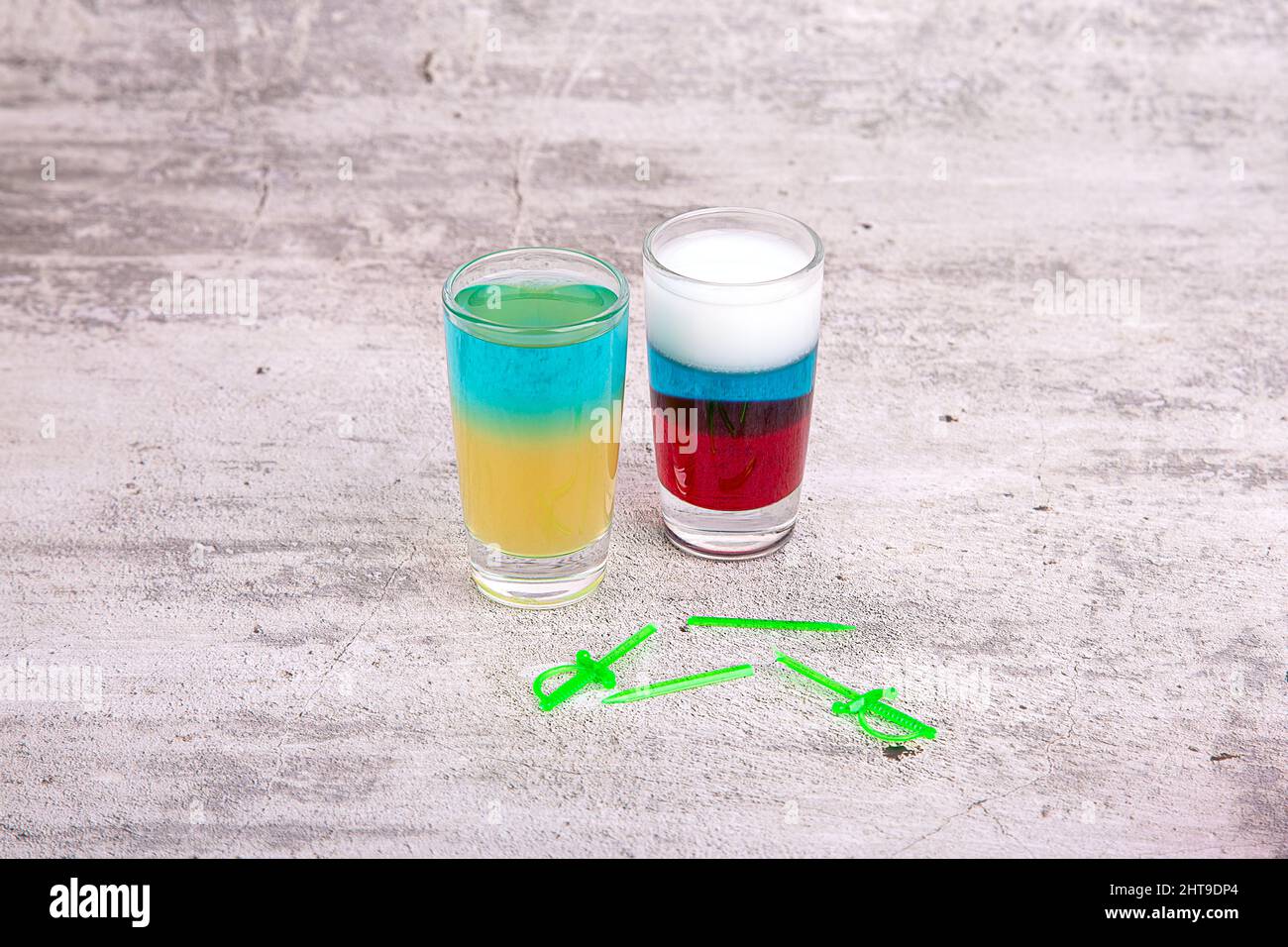 Ein zerbrochenes Schwert neben Cocktails in den Farben der Flaggen der Ukraine und Russlands Stockfoto