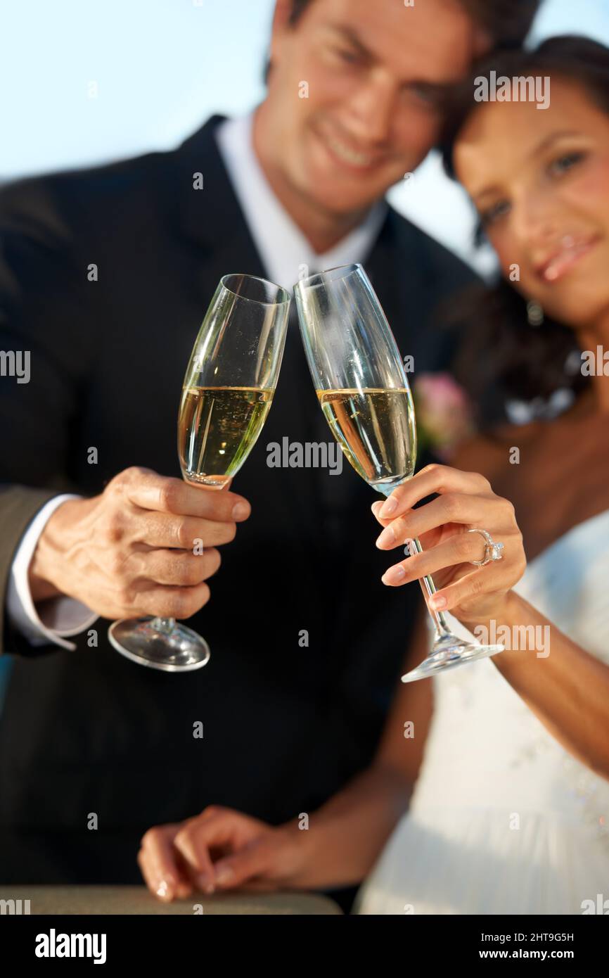 Heres zu uns. Beschnittene Ansicht einer jungen Braut und eines Bräutigams, die zusammen stehen und ihre Ehe toasten. Stockfoto