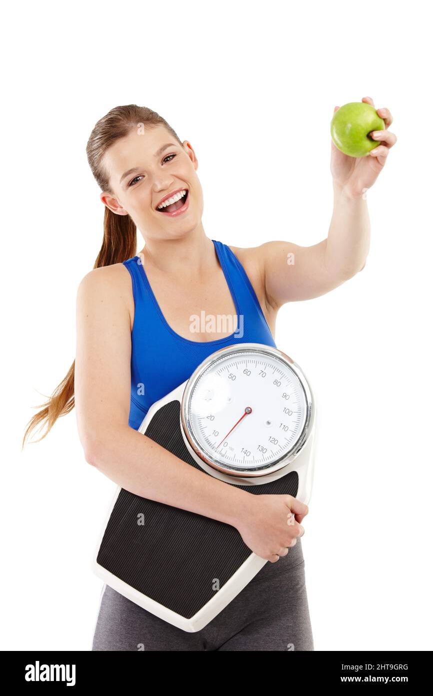 Für einen gesunden Lebensstil eintreten. Ein hübscher Teenager, der einen Apfel in der Hand hält und dabei eine Waage trägt. Stockfoto