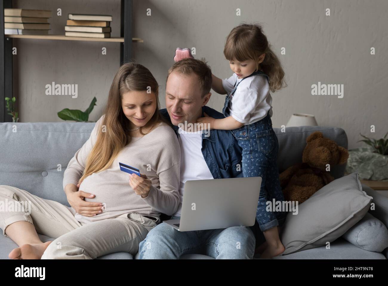 Glücklich erwartete Eltern mit Online-E-Commerce-App auf dem Laptop Stockfoto