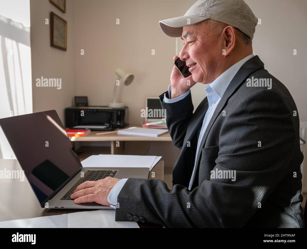 Ein leitender Büroleiter mit einem Lächeln auf dem Gesicht spricht mit Kunden am Telefon. Stockfoto