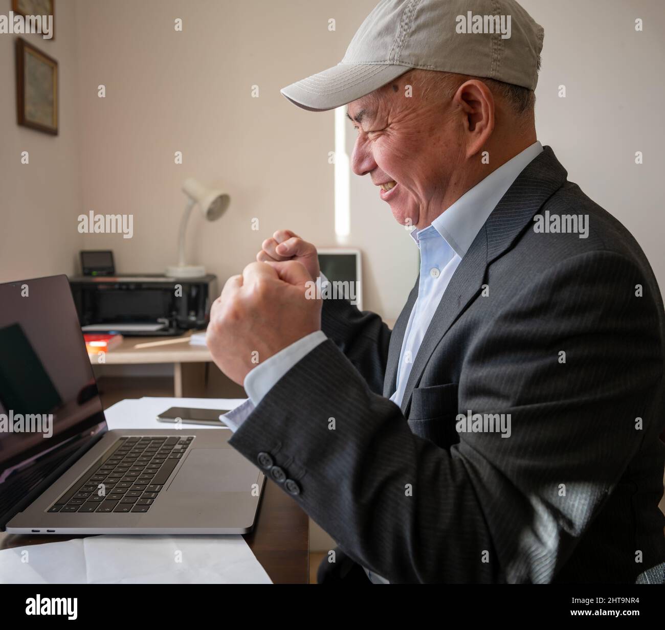 Ein Geschäftsmann im Büro mit einem aufgeregten Ausdruck nach Abschluss eines großen Online-Geschäfts. Erfolgskonzept für Unternehmen. Stockfoto