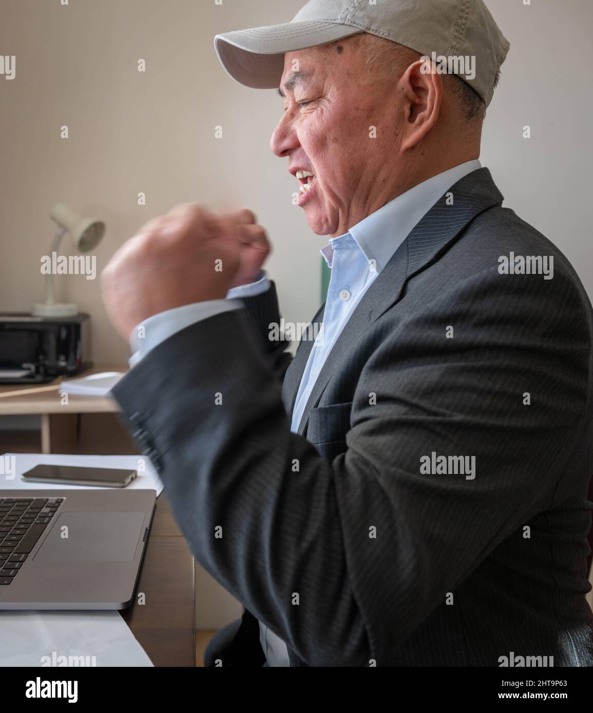 Ein Geschäftsmann im Büro mit einem aufgeregten Ausdruck nach Abschluss eines großen Online-Geschäfts. Erfolgskonzept für Unternehmen. Stockfoto