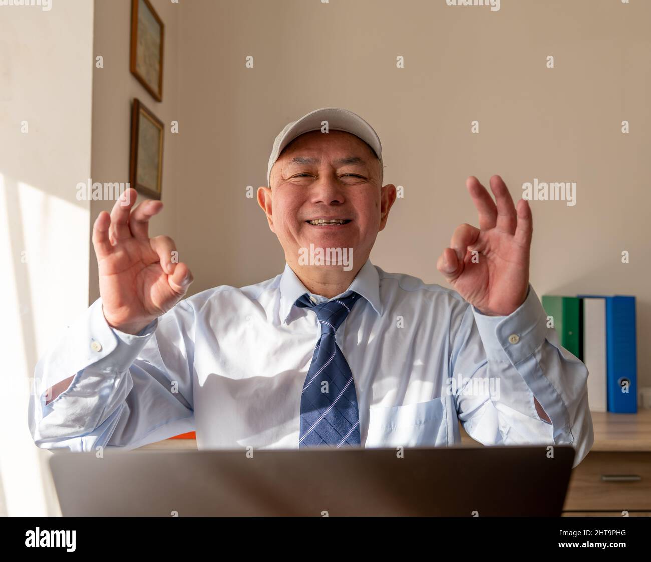 Ein lächelnder Geschäftsmann, der nach Abschluss eines großen Geschäftsabschlusses das Zeichen der „OK Hand“ gab. Stockfoto