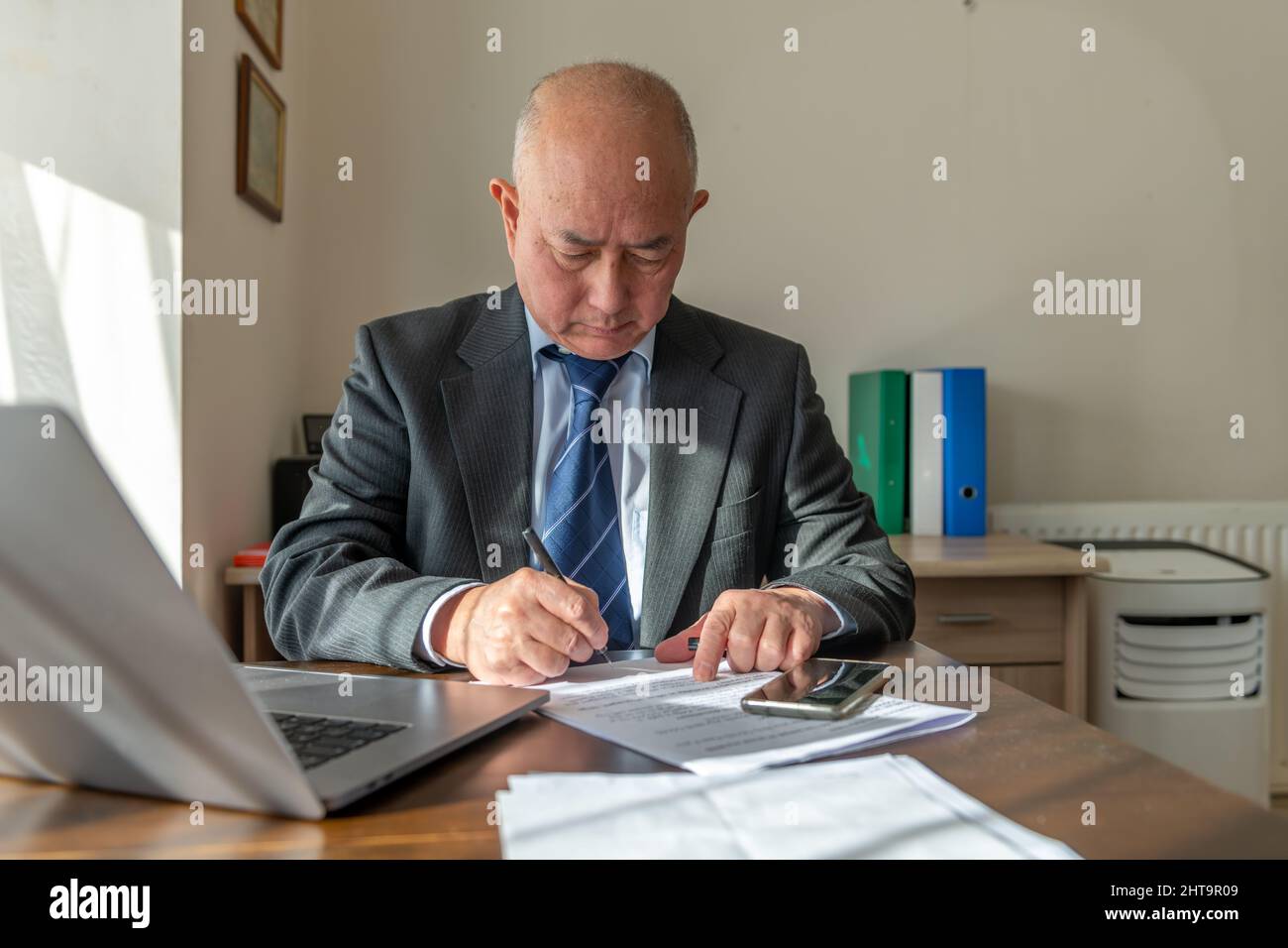 Ein leitender Angestellter, der ein Dokument im Büro unterzeichnet. Work, Bürokonzept. Stockfoto