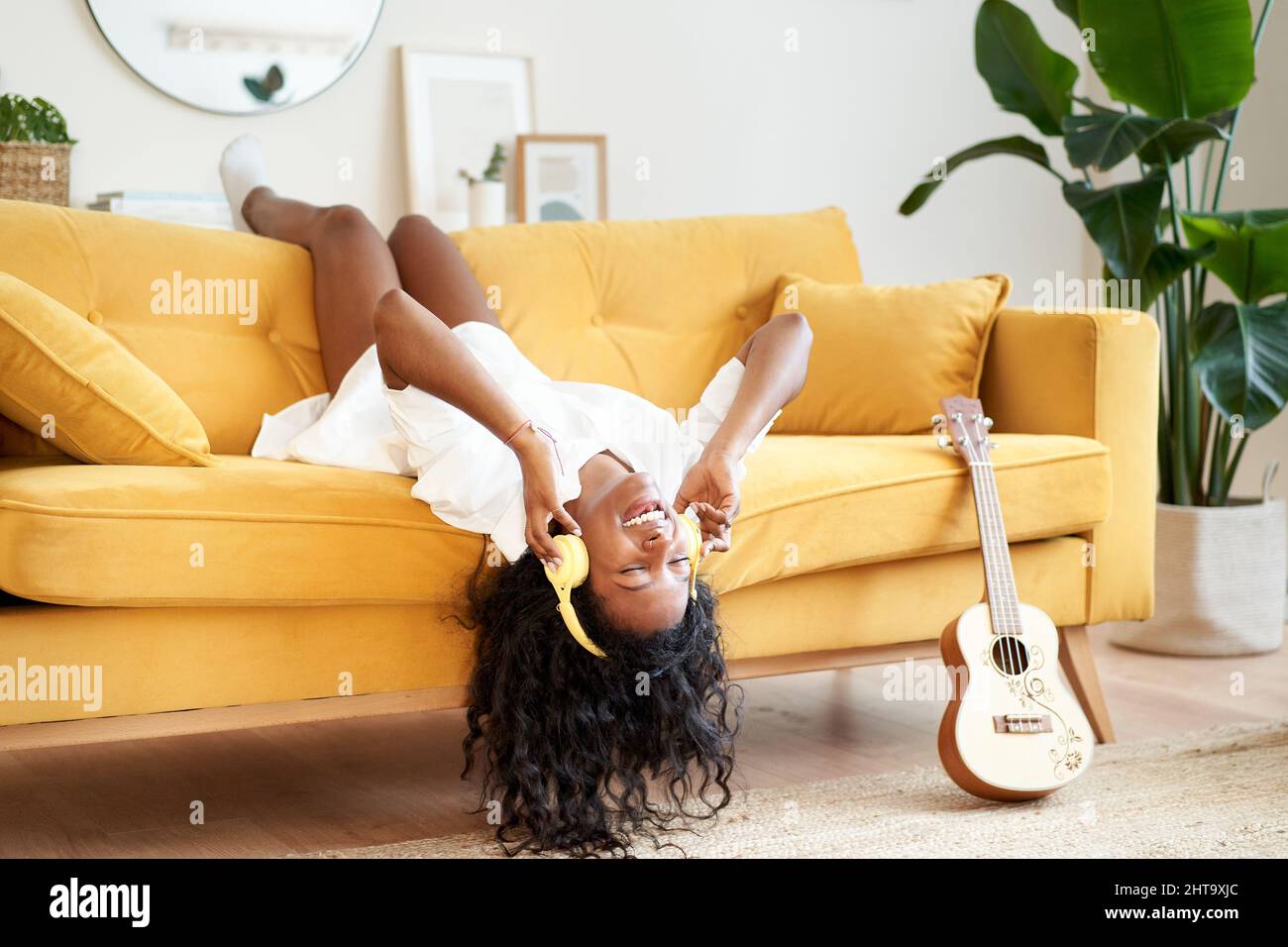Motivierte junge Frau mit Kopfhörern sitzt zu Hause auf dem Sofa. Stockfoto