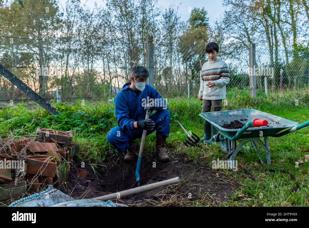 Die Gärtnerin und ihr Sohn arbeiten daran, einen Magnolienbaum zu Pflanzen Stockfoto