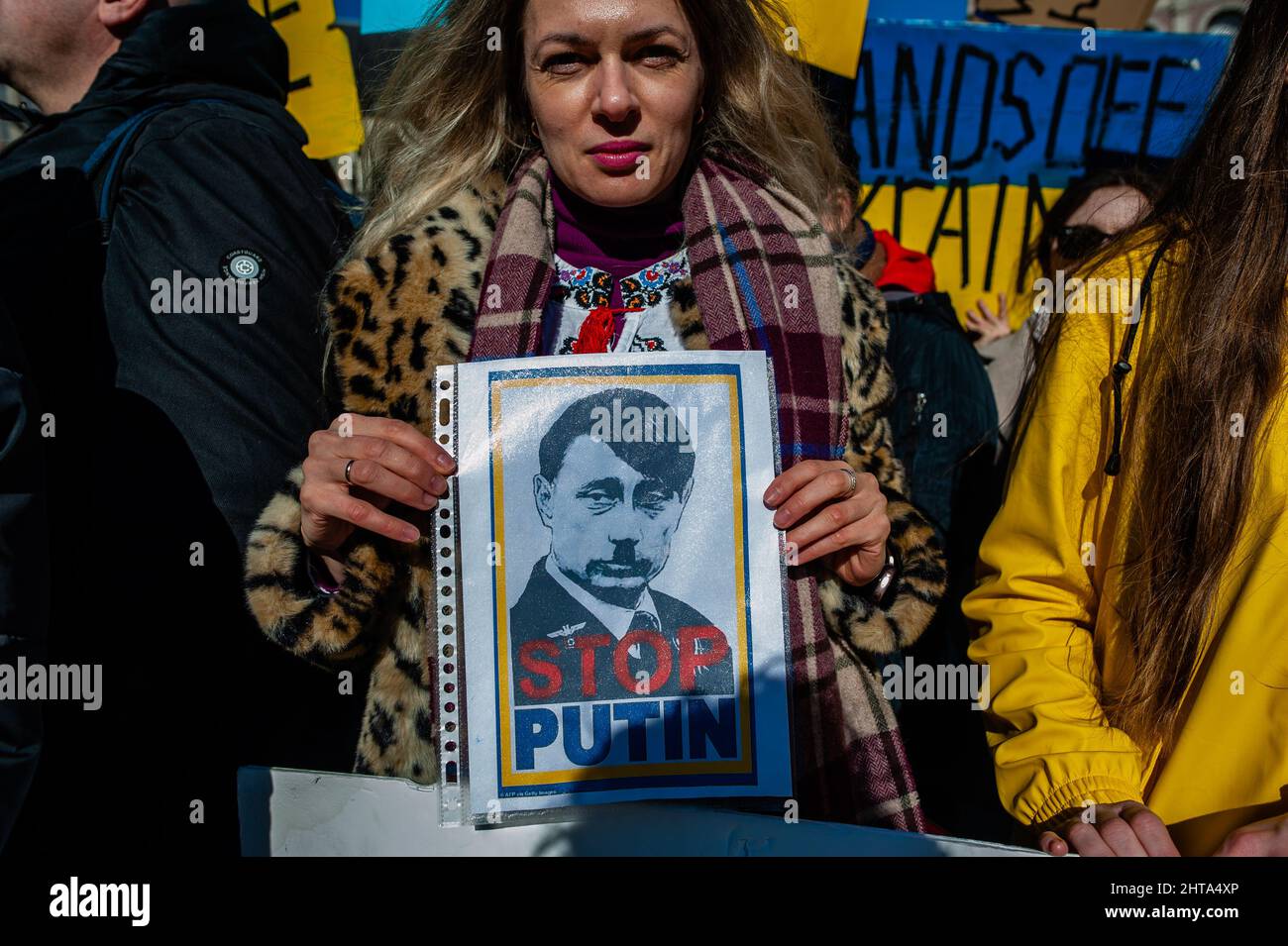 Eine Frau hat während der massiven Demonstration gegen Putins Invasion der Ukraine, die am 27.. Februar 2022 in Amsterdam organisiert wurde, ein Bild von Putin als Hitler. Nach Putins Entscheidung, die Ukraine anzugreifen, wurden am selben Tag mehrere Proteste im Zentrum der Stadt organisiert, um ihre Unterstützung für das ukrainische Volk zu zeigen. Die ukrainische Gemeinschaft, die russische Gemeinschaft und mehrere Nichtregierungsorganisationen in den Niederlanden, begleitet von Tausenden von Menschen, versammelten sich auf dem Dam-Platz, um gegen Putin und den Krieg in der Ukraine zu protestieren. (Foto: Romy Fernandez/Sipa USA) Stockfoto