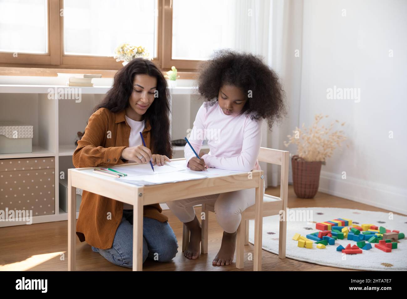 Glückliche junge afroamerikanische Mutter Zeichnung mit Tochter. Stockfoto