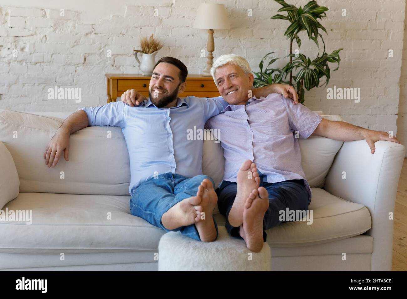 Sorgloser älterer Mann, sein Sohn, entspannt sich zu Hause auf dem Sofa Stockfoto