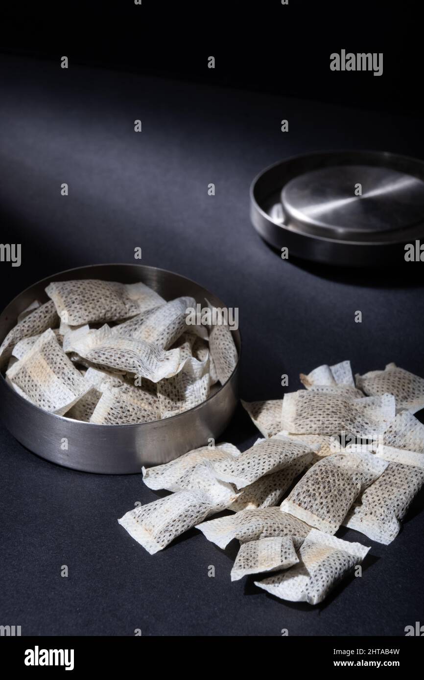 Helsinki / Finnland - 28. FEBRUAR 2022: Nahaufnahme einer metallischen schwedischen Snus-Dose mit weißen Portionen rauchloser Tabakbeutel vor dunklem Hintergrund Stockfoto