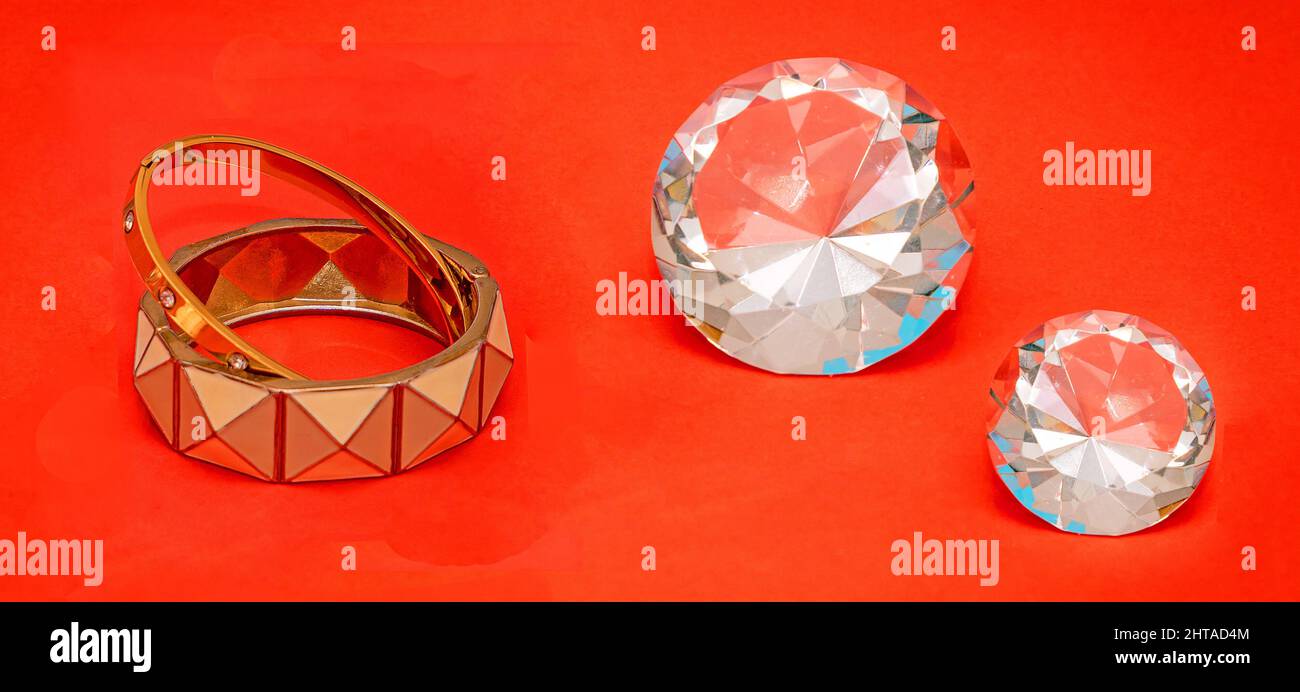 Glänzendes Gold Armreifen weiblichen Schmuck mit großen Diamanten auf der Seite auf rotem Hintergrund Stockfoto